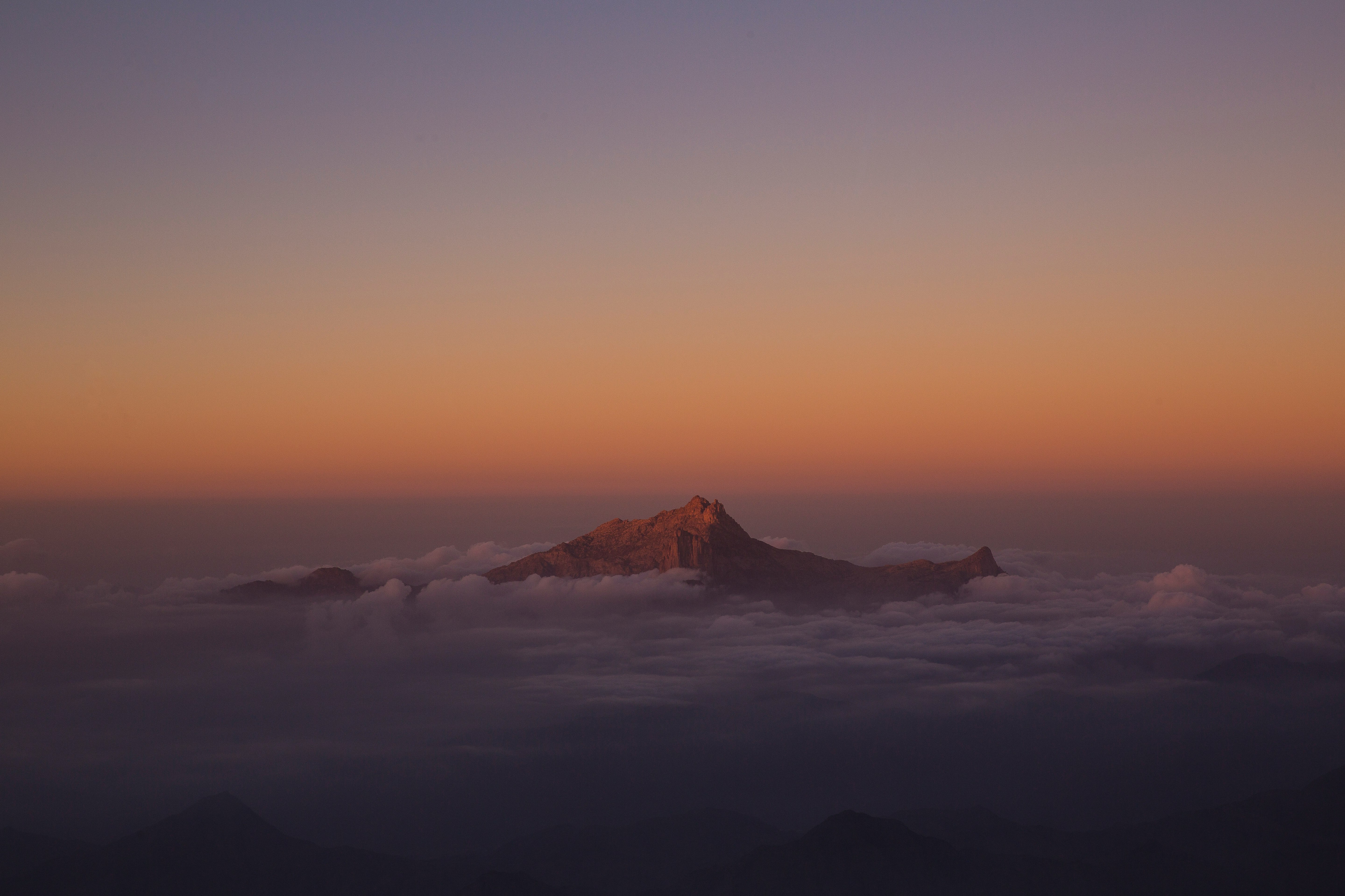 mountain covered by clouds during sunset